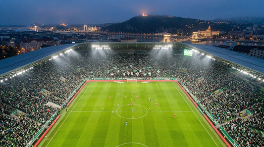 Magyar labdarúgó-stadion esti mérkőzés közben, szurkolókkal és reflektorokkal